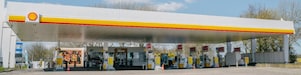 Shell gas station with signs and a brick road