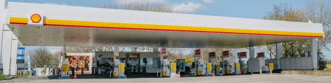 Shell gas station with signs and a brick road